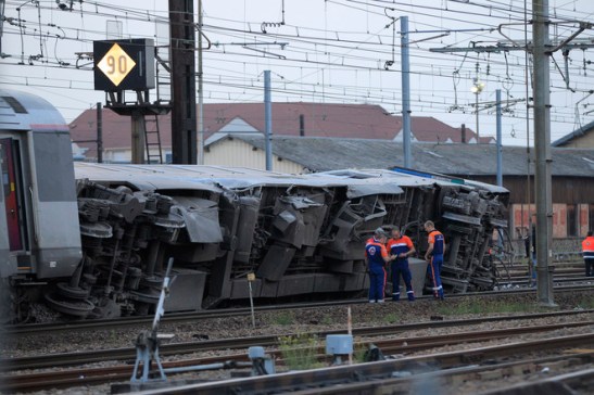Rescue workers stand next to the wreckage of a derailed intercity train at the Bretigny-sur-Orge station near Paris